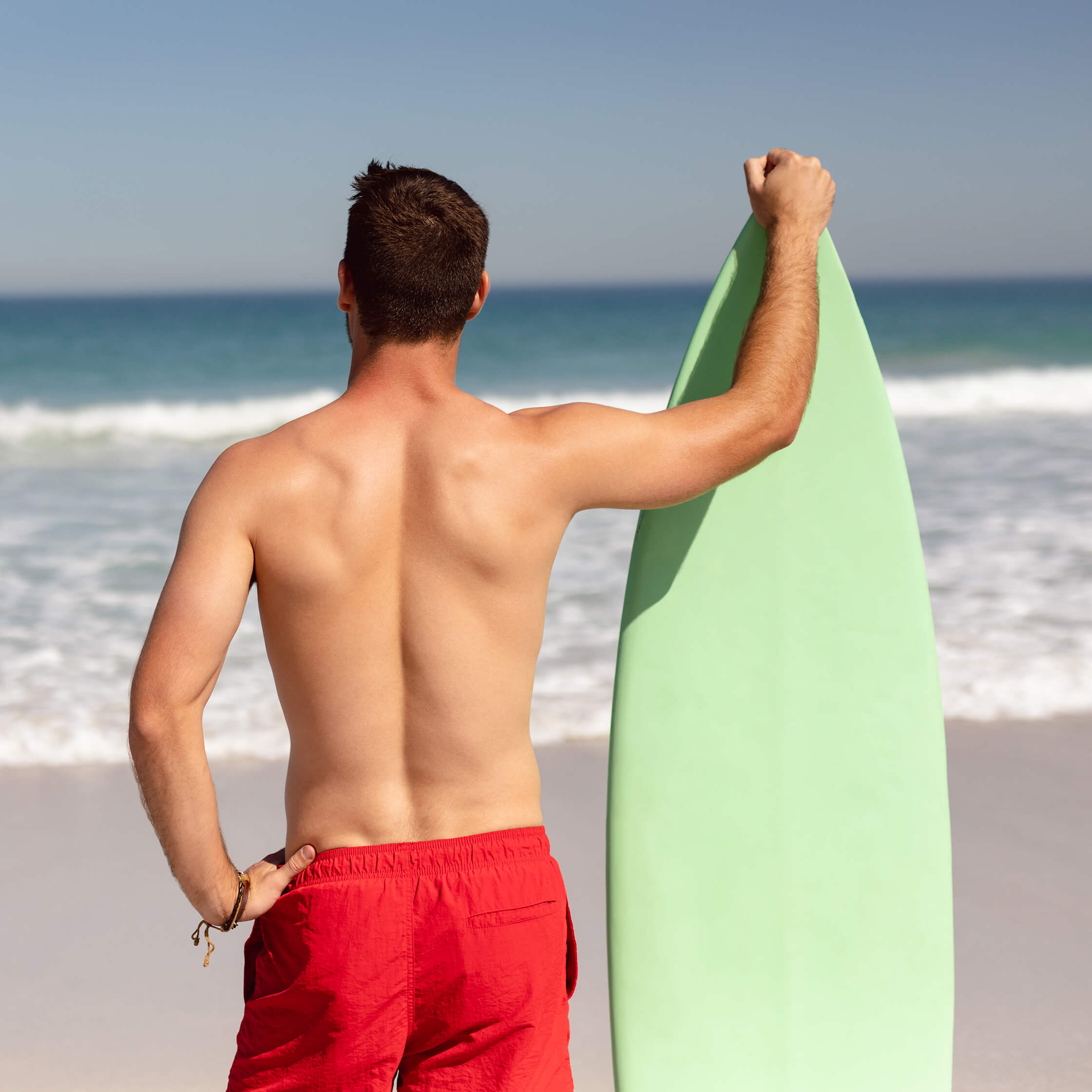 A young man prepares to surf after laser hair removal